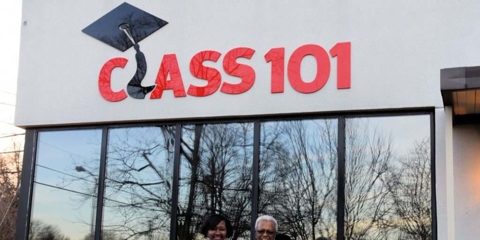 Two people smiling in front of Class 101 building